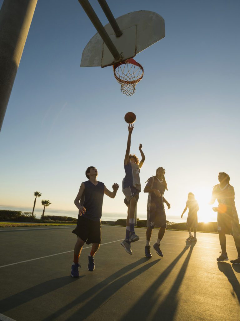 Teens playing basketball on a sunset